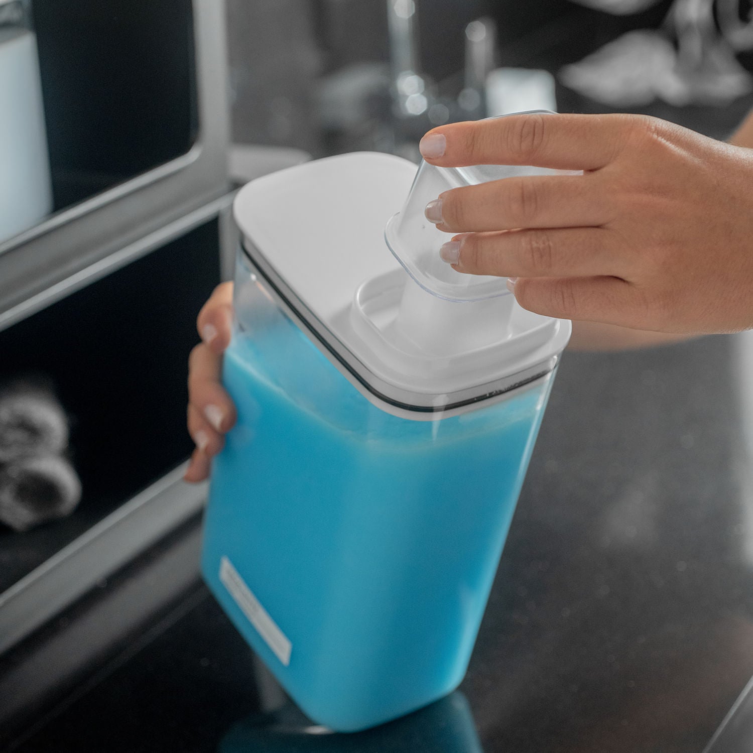Dispenser Ou com amaciante dentro e sendo colocado o copo medidor na tampa